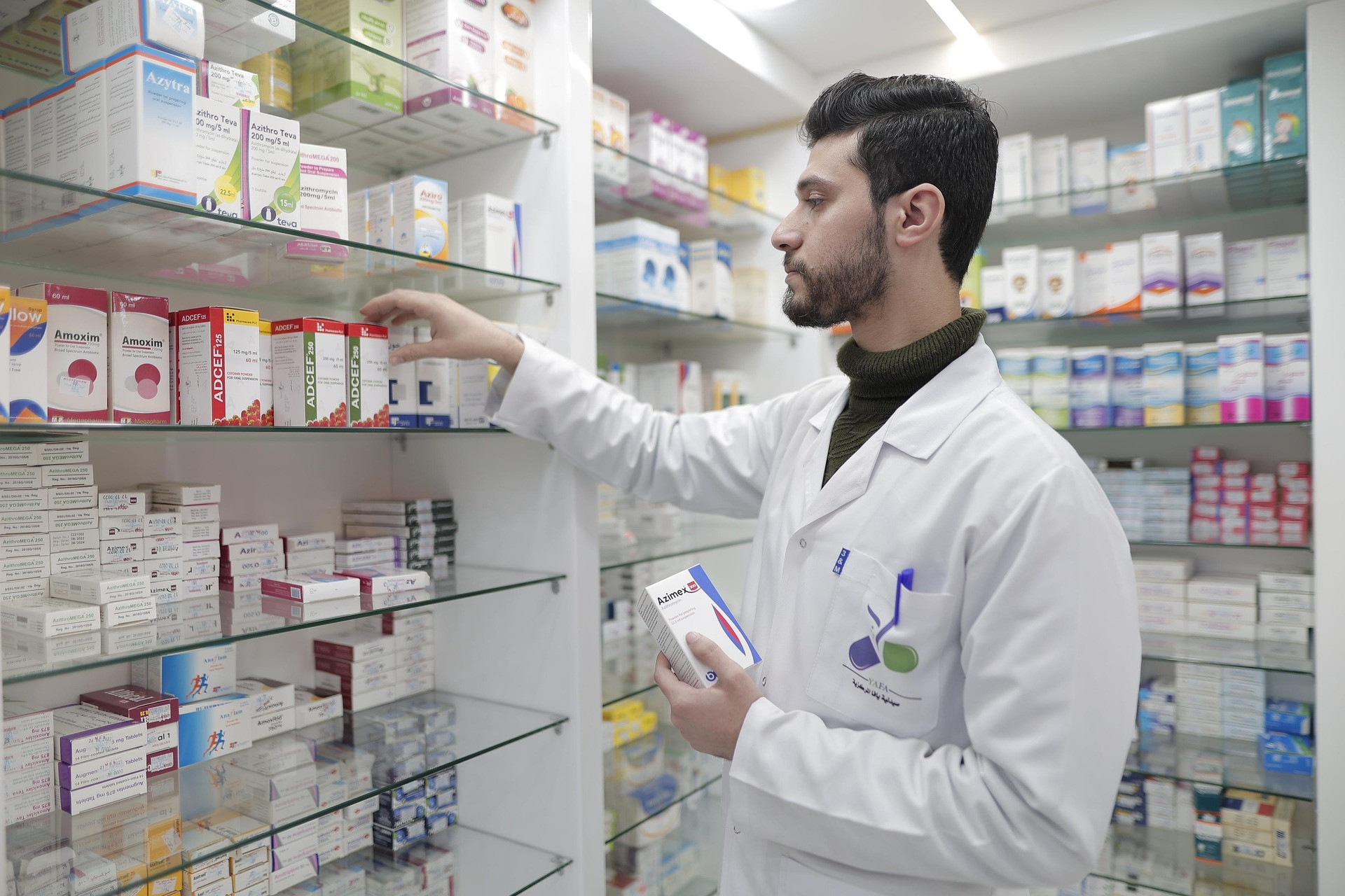 Pharmacy professional selecting medication from shelves in a pharmacy